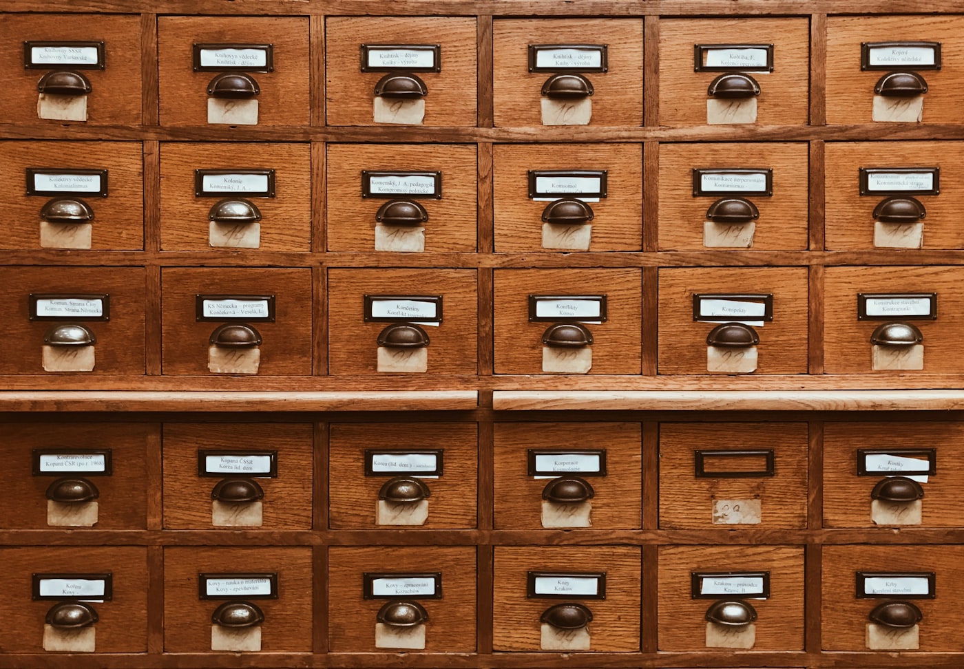 Traditional library card catalog with wooden drawers and brass label holders, representing systematic organization of knowledge and historical research methods